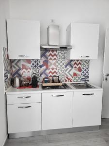 a kitchen with white cabinets and a patterned wall at Casa al Mare in Bari