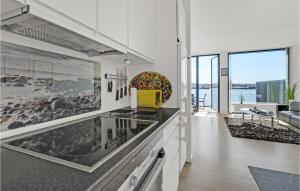 a kitchen with white cabinets and a living room at Amazing Apartment In Korsr With Kitchen in Korsør