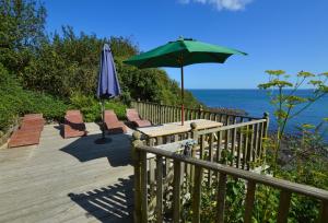 a deck with chairs and an umbrella and a table at Prospect House in Coverack