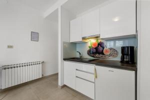 a kitchen with white cabinets and a bowl of fruit on the counter at Guesthouse Casa Nova in Poreč
