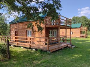 a wooden cabin with a large deck in the grass at Uroczy domek (+ sauna) w Nowej Jedlance in Jedlanka Nowa