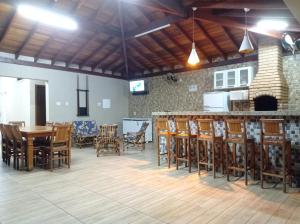 una sala da pranzo con tavoli, sedie e un bar di Casa Temporada Belo Por do Sol a Olímpia