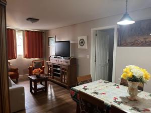 Ap Gramado - ALTO PADRÃO في غرامادو: غرفة معيشة مع طاولة وتلفزيون