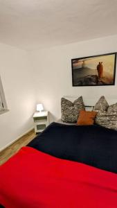 a bedroom with a bed with a red blanket at FeWo im Lehm-Fachwerkhaus Erfurt mit 3 einzelnen Schlafzimmern je mit TV in Erfurt