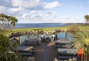 a deck with tables and chairs and the ocean at Sunflower Cottage - Gonwin Manor in Carbis Bay