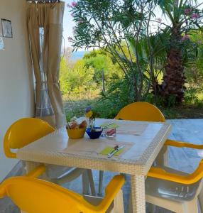 une table avec des chaises jaunes, une table blanche, une table et des chaises dans l'établissement Casette Santini B&B, à Casalbordino