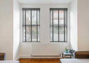 sala de estar con 2 ventanas y radiador en Two Bed Flat in Bush Hill Park, en Enfield