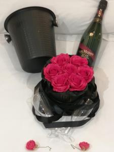 a bottle of wine and a bouquet of pink roses at l'Antre coquin in Béthune