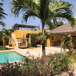 a house with a palm tree and a swimming pool at Toubana Lodge in Ngaparou