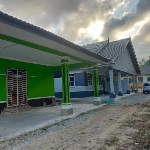 a green and white building with green columns at Homestay ainnor in Pasir Puteh