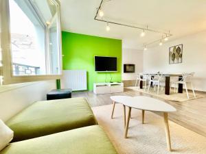 a living room with a green wall and a table at L'Orangerie - T4 - Centre ville - Wifi Fibre - Au calme - Lumineux in Lorient