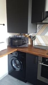 uma cozinha com uma máquina de lavar roupa e um micro-ondas em Studio 2 lits jumeaux 1 station Tram aéroport Orly em Athis-Mons