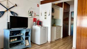 a kitchen with a refrigerator and a tv on a wall at Sun & Sea 509 in Sesimbra
