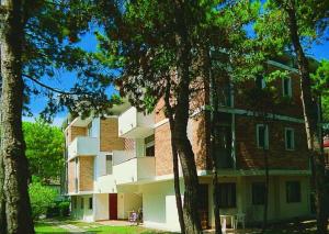 un grande edificio in mattoni con alberi di fronte di Lignano Pineta a Lignano Sabbiadoro