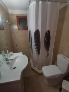 uma casa de banho com um WC e uma cortina de chuveiro com penas em Antoneiko house 