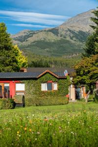 una casa cubierta de hiedra con montañas en el fondo en Sukal en El Bolsón