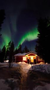 an aurora over a cabin in the snow at night at Villa Wältti in Rovaniemi