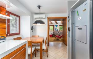 a kitchen and dining room with a table and a refrigerator at Gorgeous Home In Sveti Vid Dobrinjski With House A Panoramic View in Gostinjac