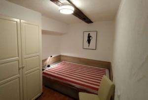 a small bedroom with a bed with a red and white striped blanket at Downtown Switzerland/Bodensee/Zurich in Ermatingen
