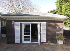 a small red brick house with a white door at Lovely 1-bedroom rental with a pool in Cape Town