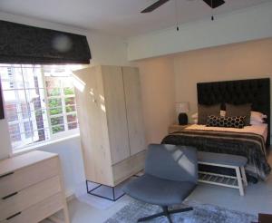 a bedroom with a bed and a desk and a chair at Lovely 1-bedroom rental with a pool in Cape Town
