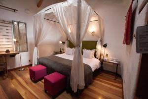 a bedroom with a canopy bed with pink stools at ARQUEOLOGO EXCLUSIVE SELECTION - Casa Peralta in Cusco