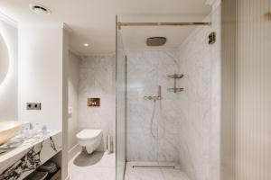 a white bathroom with a shower and a toilet at Hotel 717 in Amsterdam