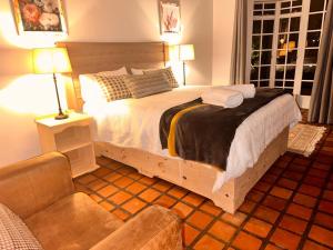 um quarto com uma cama grande e uma cadeira em WOODS GUEST HOUSE em Middelburg