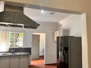 a kitchen with a sink and a black refrigerator at WOODS GUEST HOUSE in Middelburg