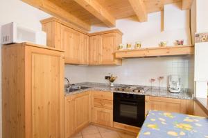 eine Küche mit Holzschränken, einer Spüle und einer Mikrowelle in der Unterkunft Chalet Tremalzo in Ledro