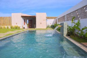 a pool with a water fountain in front of a building at Pousada Sal e Sol in São Miguel do Gostoso