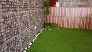 un jardín con una pared de ladrillo y césped verde en Dream Garden Hotel, en Klang