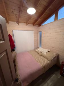 a small bedroom with a bed in a wooden room at Cabaña 7 pax + cabañita 4 pax. By Terrabahia in Pichidangui