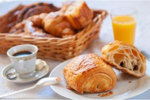 a plate of pastries and a cup of coffee and a basket of bread at Villa Reims Epernay Champagne Vineyard in Villers-Allerand