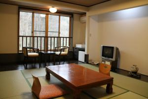 a living room with a table and a television at Gensenkan in Nasushiobara