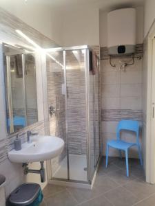 baño con lavamanos y ducha con silla azul en SOLELUNA, en Albenga