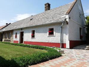 Biały dom z czerwonymi oknami i czerwonymi kwiatami w oknach w obiekcie Péringer Udvarház w mieście Mencshely