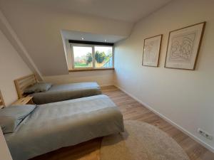 two beds in a room with a window at Casa de Schans - 6 persoons vakantiehuis in Landgraaf