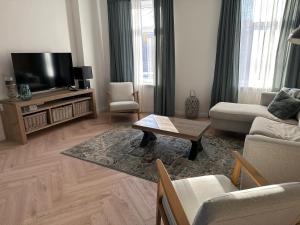 a living room with a couch and a tv at Casa de Schans - 6 persoons vakantiehuis in Landgraaf