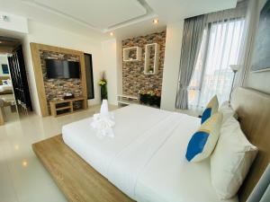a bedroom with a large white bed and a television at Buasri By Ohm in Patong Beach