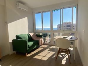 uma sala de estar com um sofá verde e uma mesa em Estudio renovado con vista al mar em Torremolinos