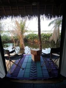 Zimmer mit 2 Stühlen, einem Tisch und Wasser in der Unterkunft Glamping Lakeview Ouidah 