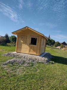 una pequeña casa de perros de madera en un campo de hierba en Gazdov dvor, en Vavrišovo