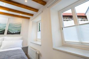 um pequeno quarto com 2 janelas e uma cama em Stadtmauer-Apartments - Neue helle Studio Wohnung direkt an der historischen Stadtmauer em Nördlingen