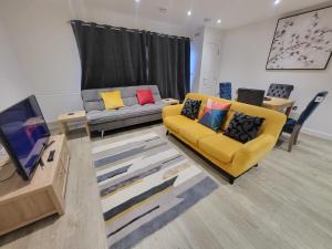 a living room with a yellow couch and a tv at Garland Apartment, Greenhithe 3 in Dartford