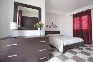 a bedroom with a bed and a dresser with a mirror at Casa Vacanza Nina in Pozzallo