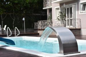 a swimming pool with a water fountain in a yard at Doce Canela - Pousada de Charme in Canela