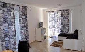 a living room with a couch and a tv and a window at Apartments Sunshine & Smile in Klimno