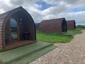 Deux cabanes avec une table dans l'herbe dans l'établissement Poplars Farm Site Glamping Pods, à Hulland