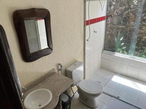 a bathroom with a toilet and a sink and a mirror at Pousada Veredas, Café e 08 cachoeiras na propriedade incluso ! in Cavalcante